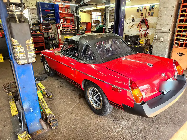 A classic red convertible inside the workshop bay